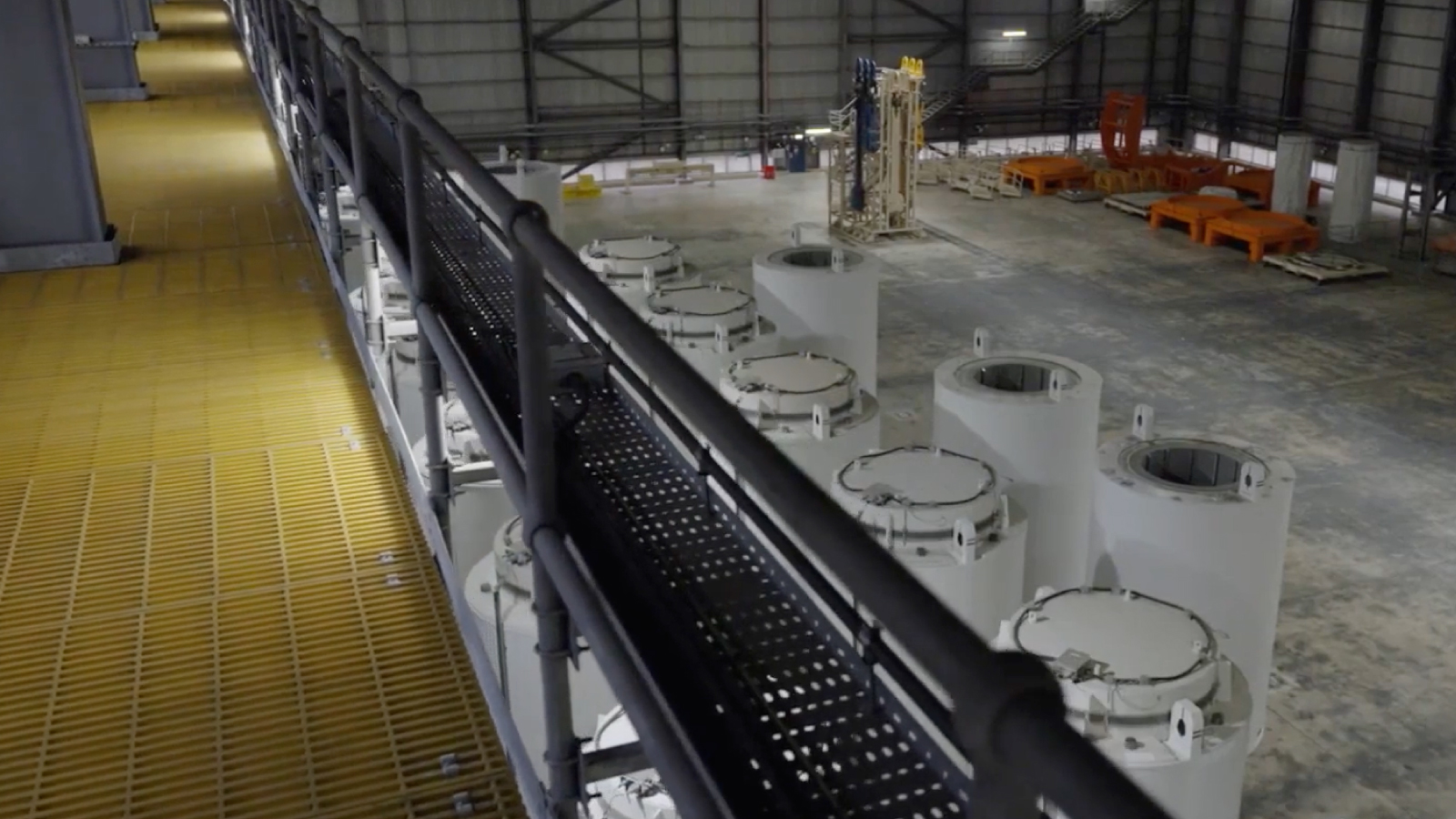 Sizewell C Customer Story Illustrative Image 2 An overhead view of an industrial facility interior with large cylindrical components, metal walkways, and equipment spread across a spacious warehouse.