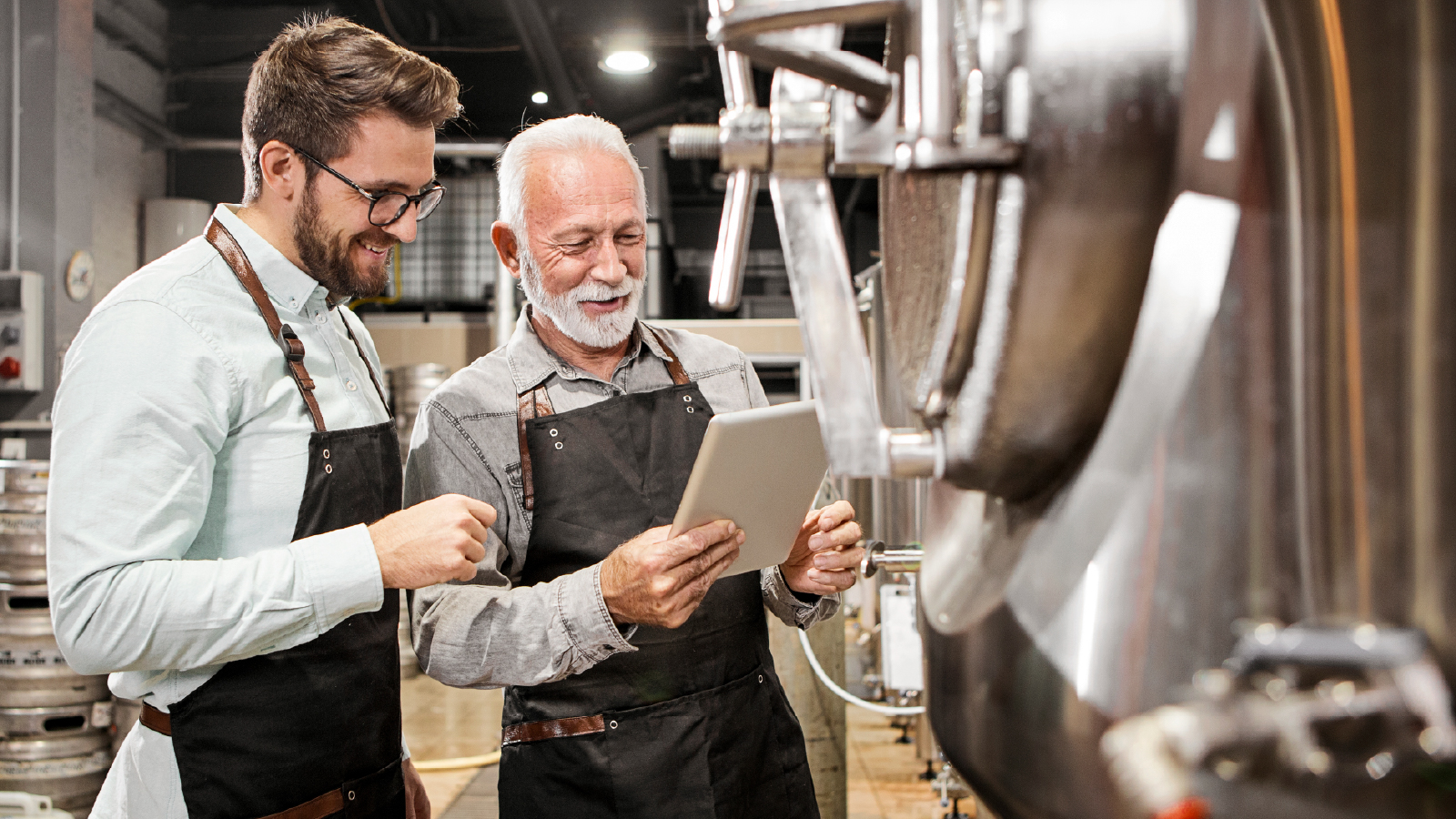 ABInBev Ilustrative image 1 Two men wearing leather aprons inspecting brewing equipment