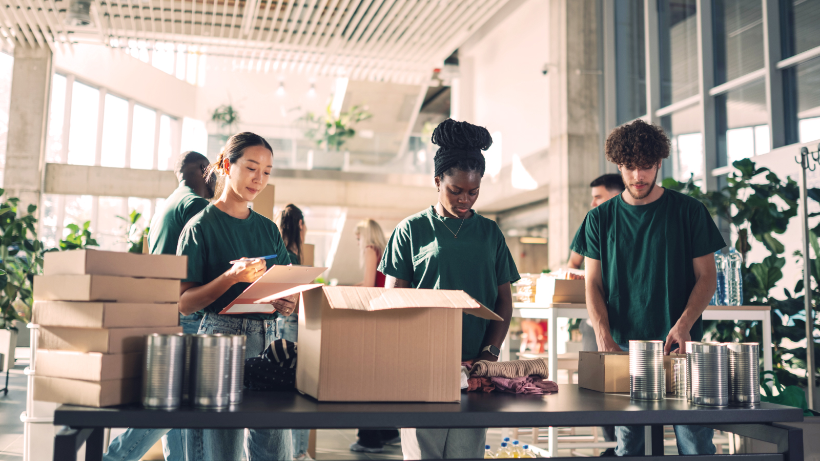 Group of volunteers in a bright workspace organizing donations and packing boxes for a local charity initiative.