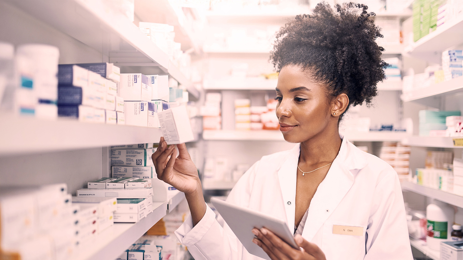 Anaplan white paper on integrated business planning for pharma. The text highlights “From concept to adoption — and value,” with an image of a pharmacist holding a tablet while examining a medicine box in a well-stocked pharmacy aisle.