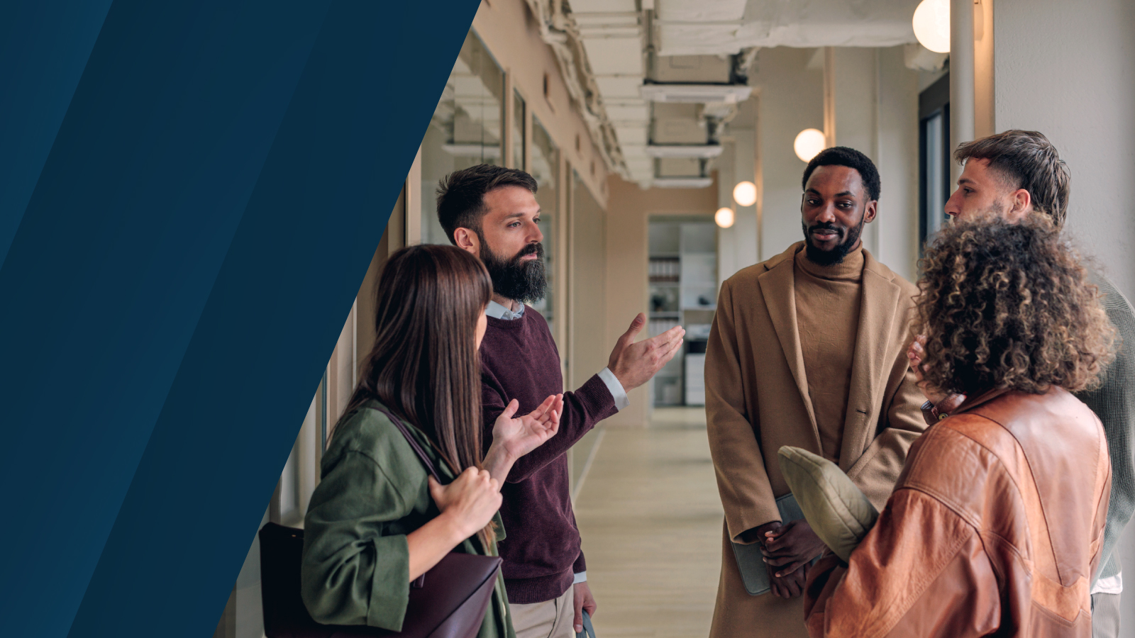 Groupe utilisateurs Anaplan France. Image de cinq personnes échangeant dans un couloir moderne et éclairé.