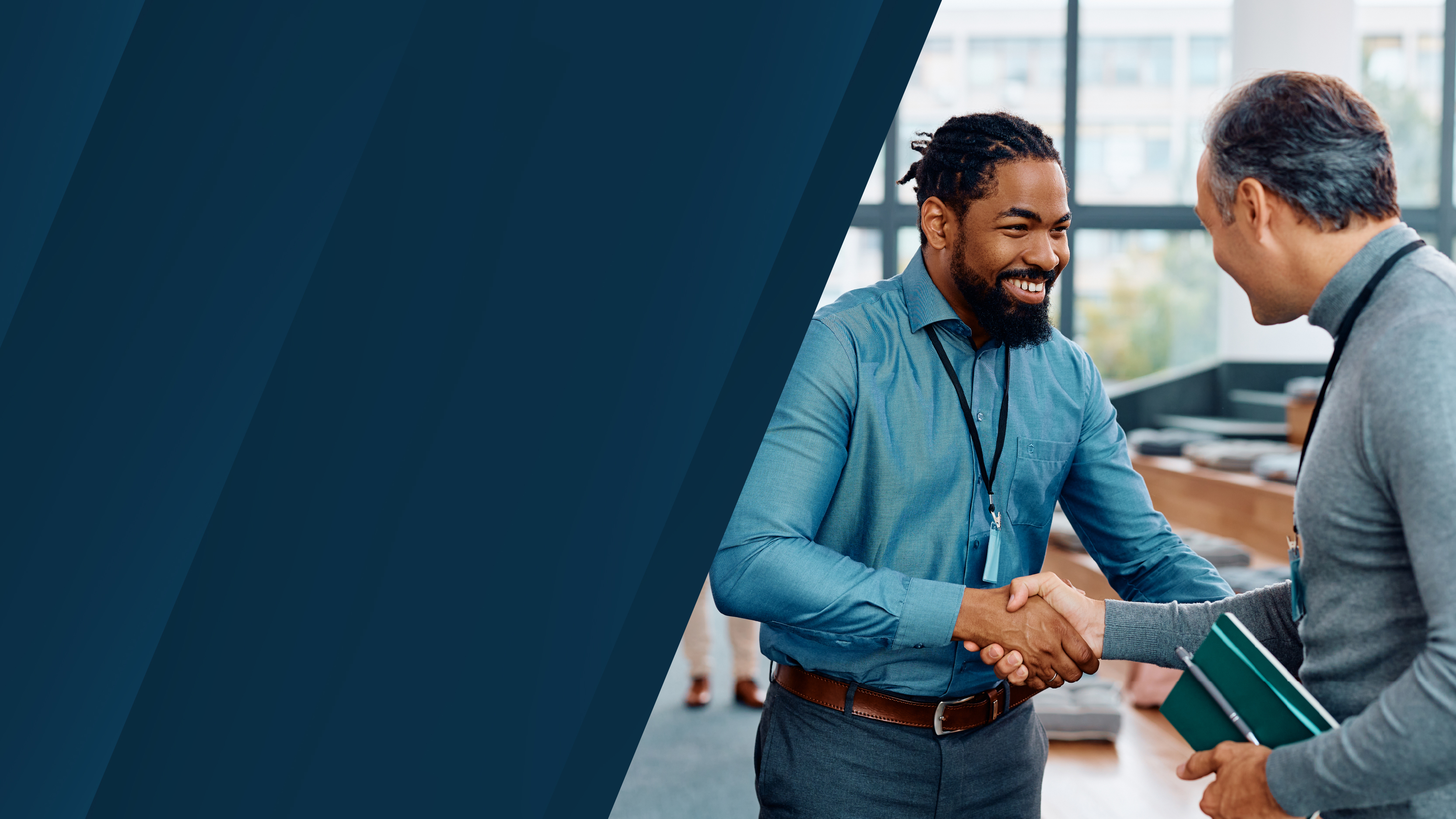 Two business professionals wearing conference badges shaking hands in a modern event space, with dark blue diagonal graphic panels on the left.