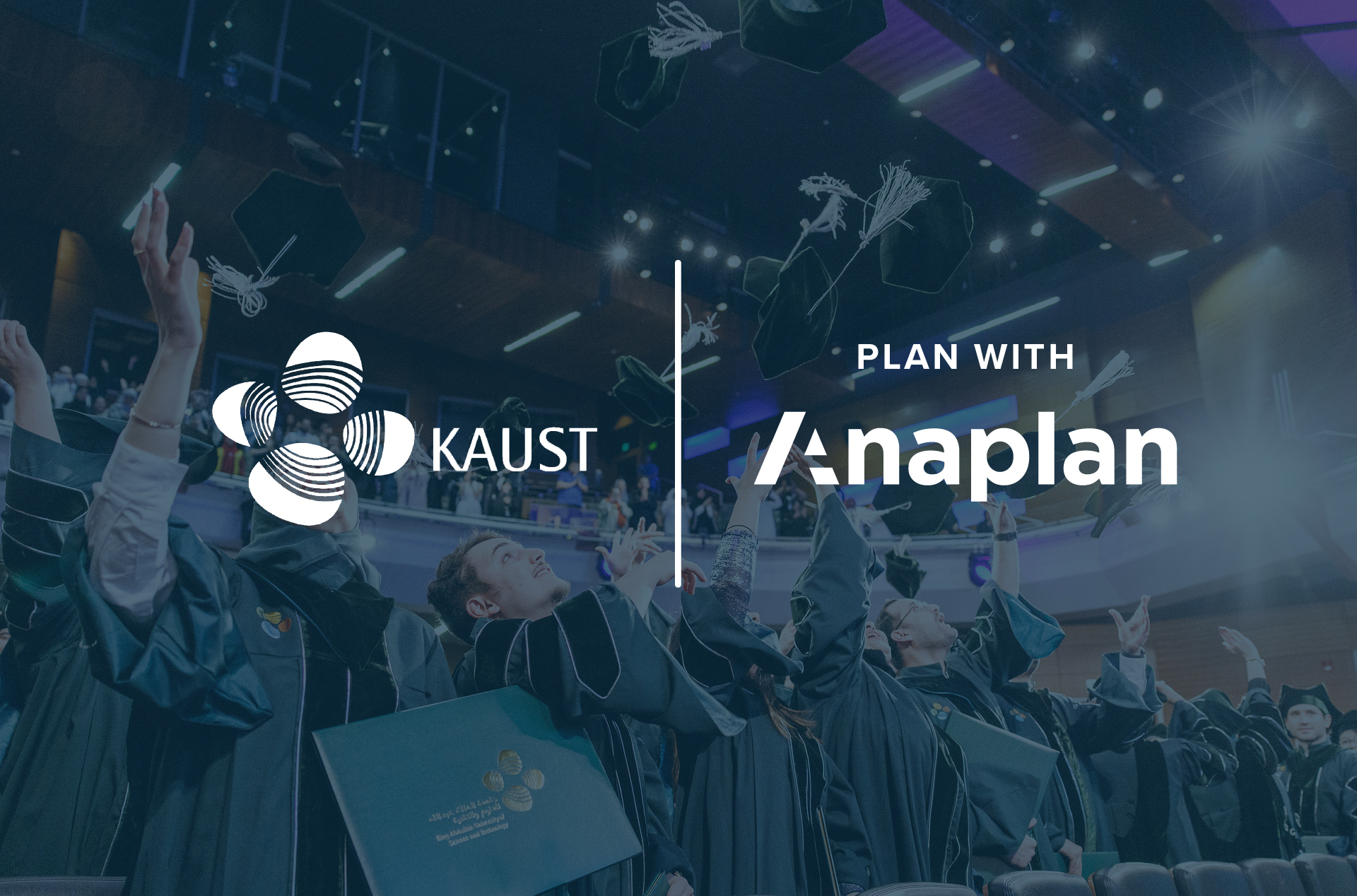 KAUST and Anaplan Logos displayed center. Graduates in academic regalia cheer and toss caps in the air inside a modern auditorium.