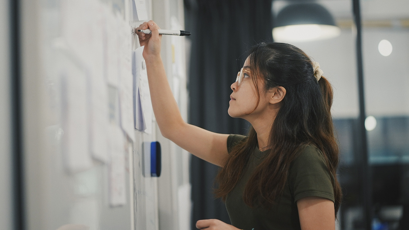 Asiatische Frau schreibt etwas auf ein Whiteboard