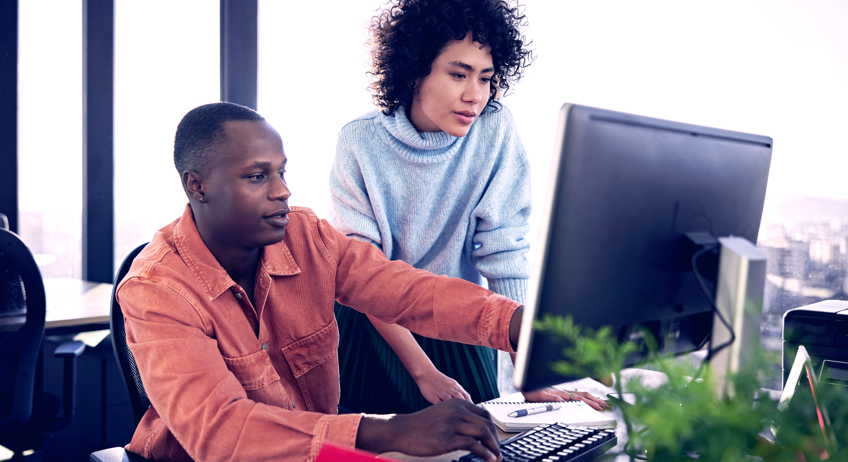 Man and woman collaborating on a computer program in an office setting