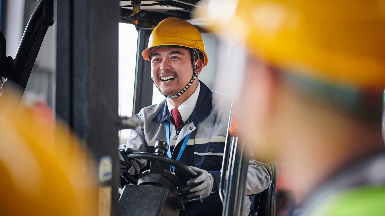 A man smiling driving a fork lift