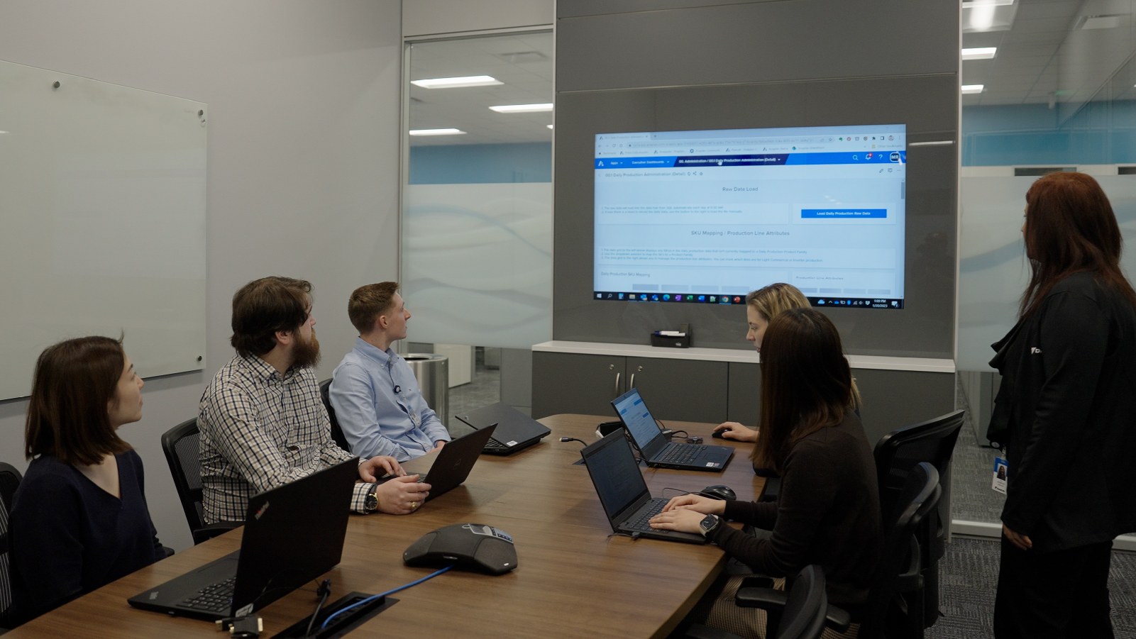 A team in a meeting room looking at a screen