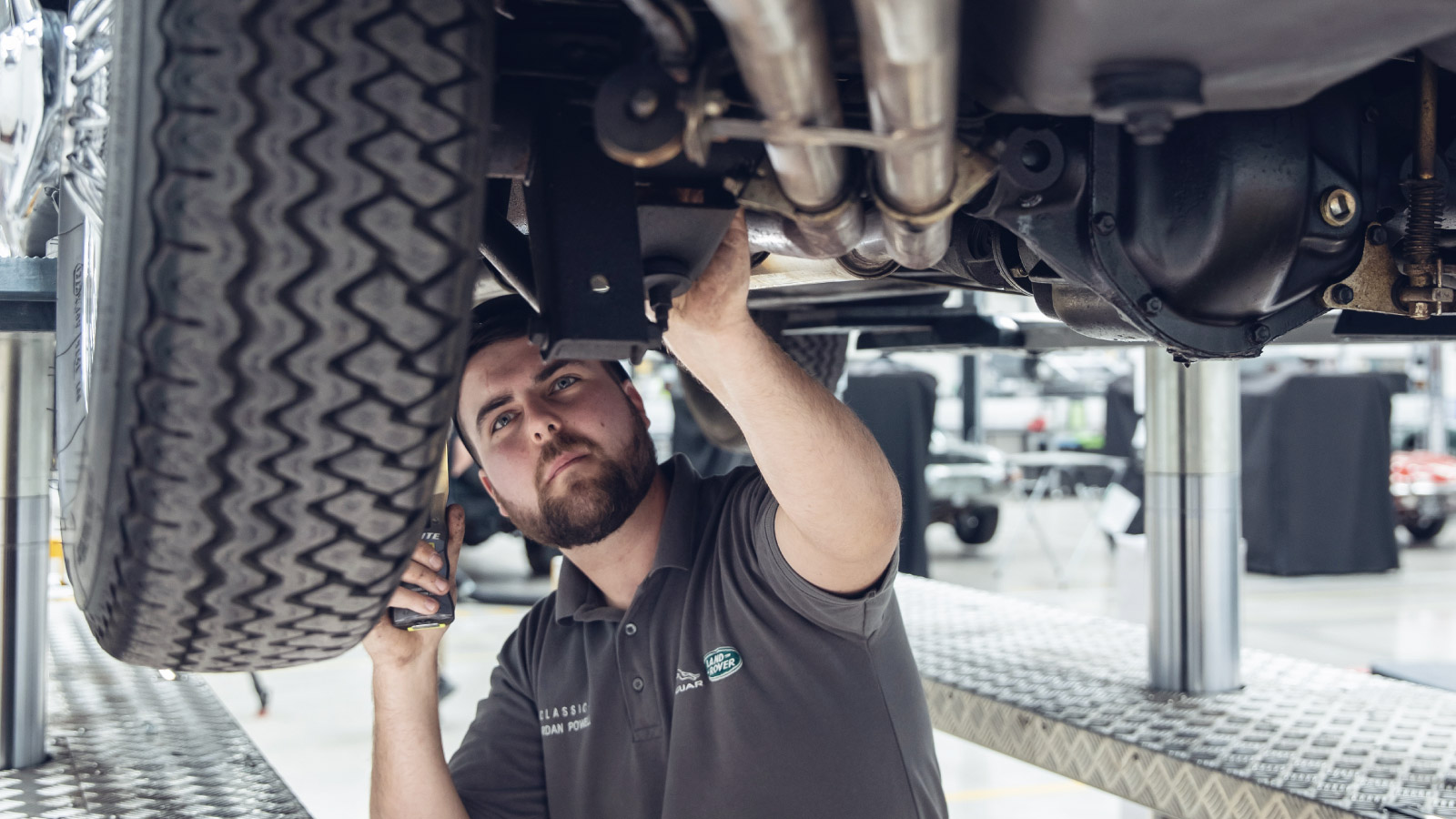 Mechanic running a diagnosis under a car being lift up 