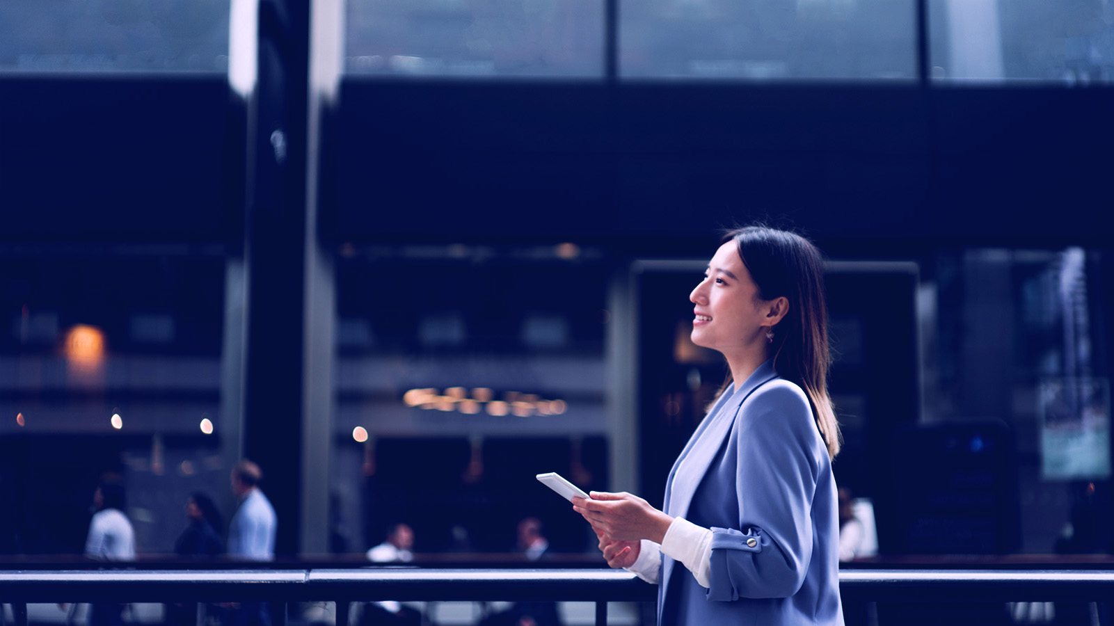 Photo of woman in front of glass building holding a small notepad