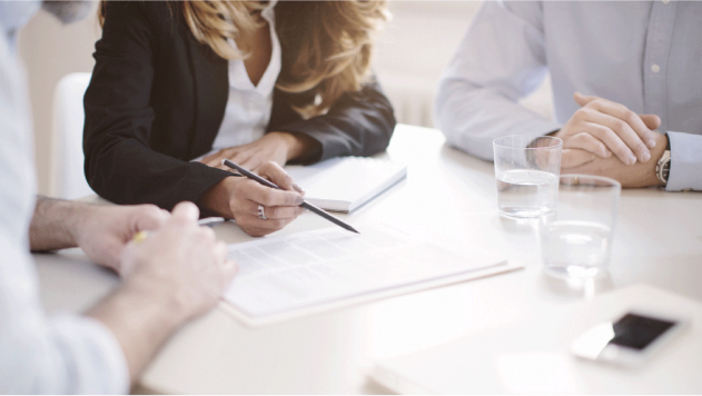 Anaplan_CustomerPage_CaseStudy Coworkers sitting at a table reviewing a document