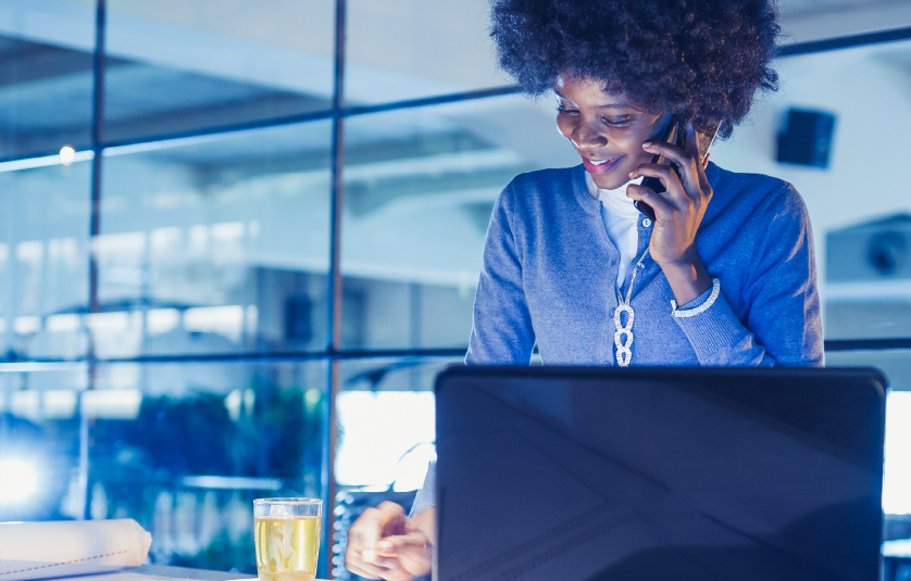 Business woman in an office having a conversation on the phone while also working on a laptop