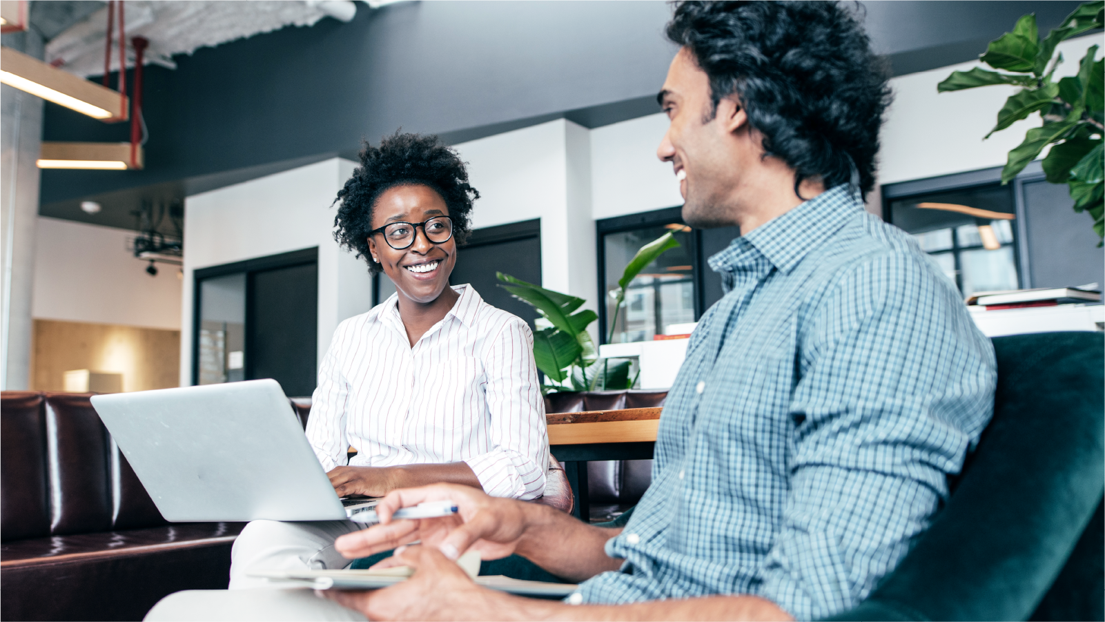 Coworkers sharing a laptop and smiling at each other