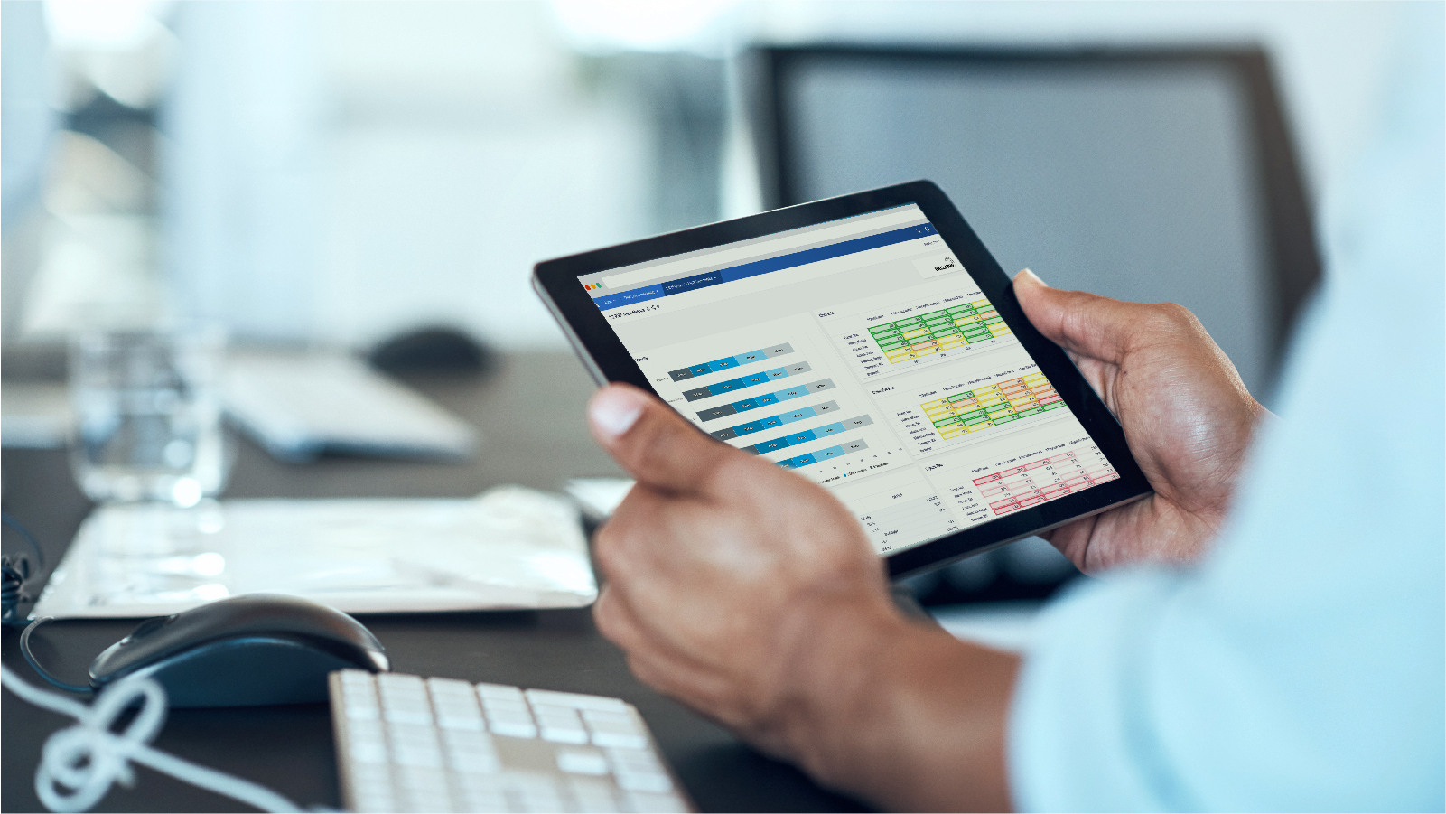 Two hands holding a tablet at a desk