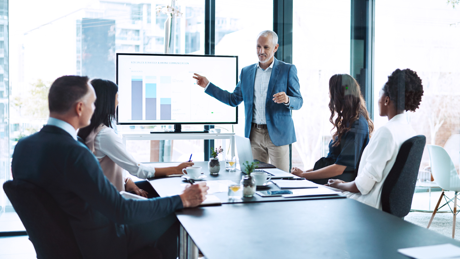 one man presenting chart to four other coworkers in an office