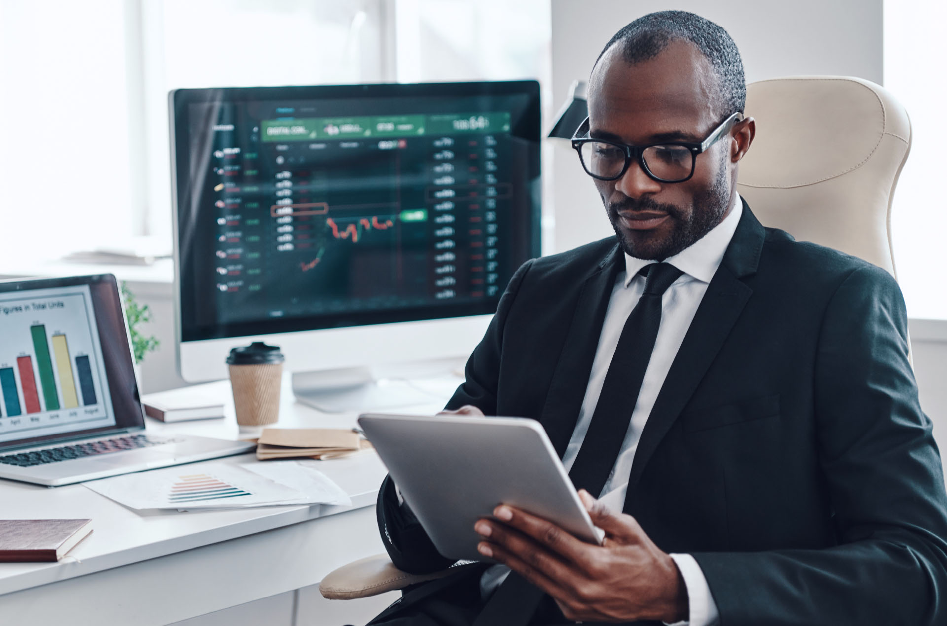 Man sitting at computer studying something on a tablet