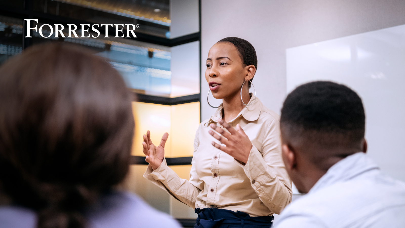 Woman standing presenting to two other seated colleagues