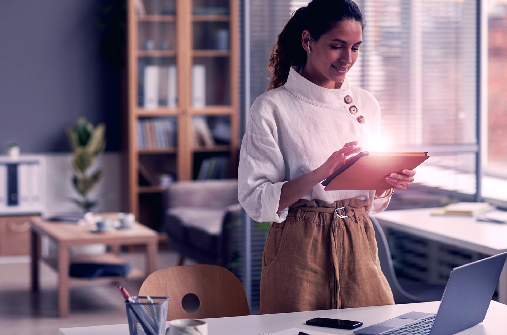 Woman in office scrolling on tablet