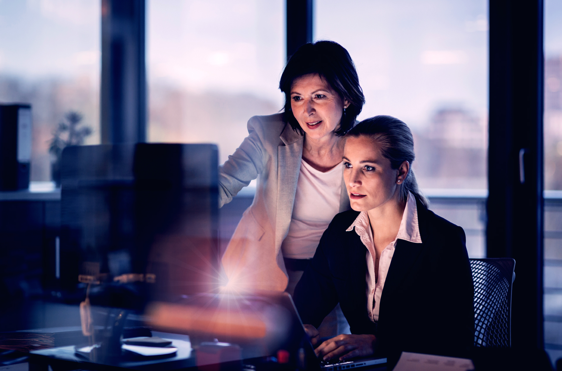 two businesswomen looking at the same computer monitor