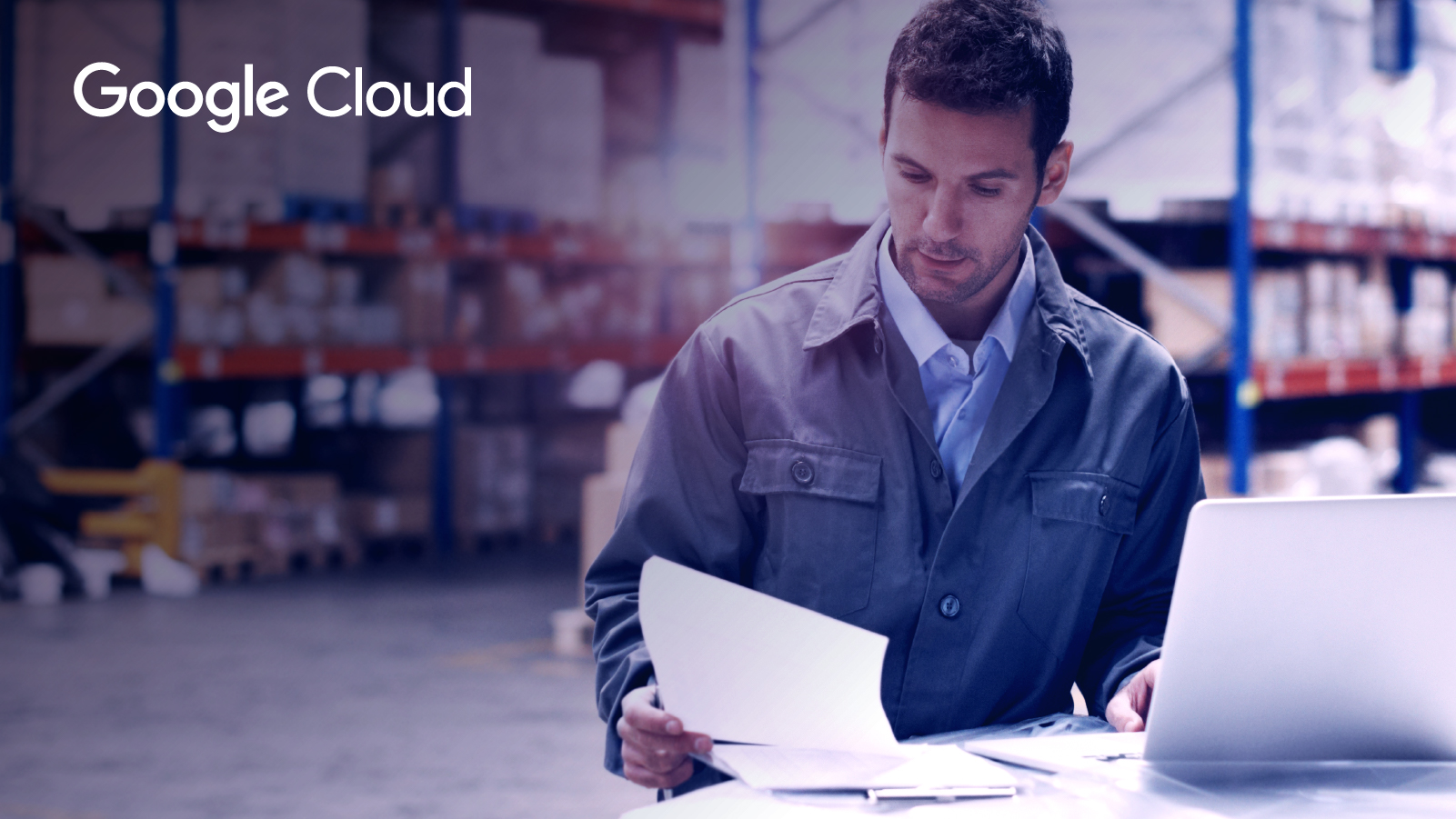Man working on computer and reviewing paperwork in warehouse