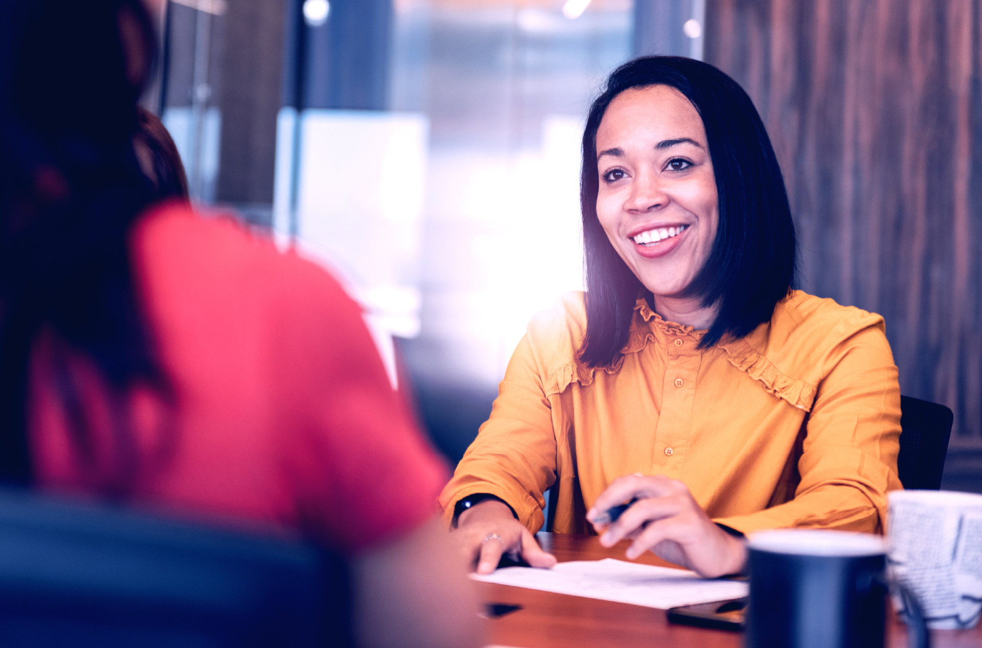 Two women speaking over conference table