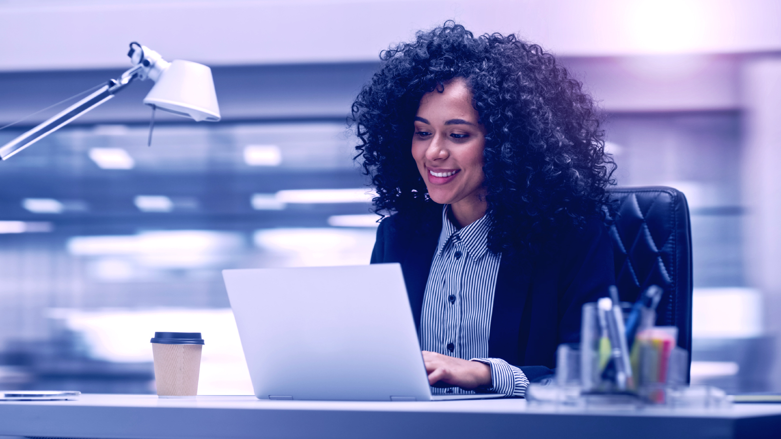 woman smiling while working on computer at desk