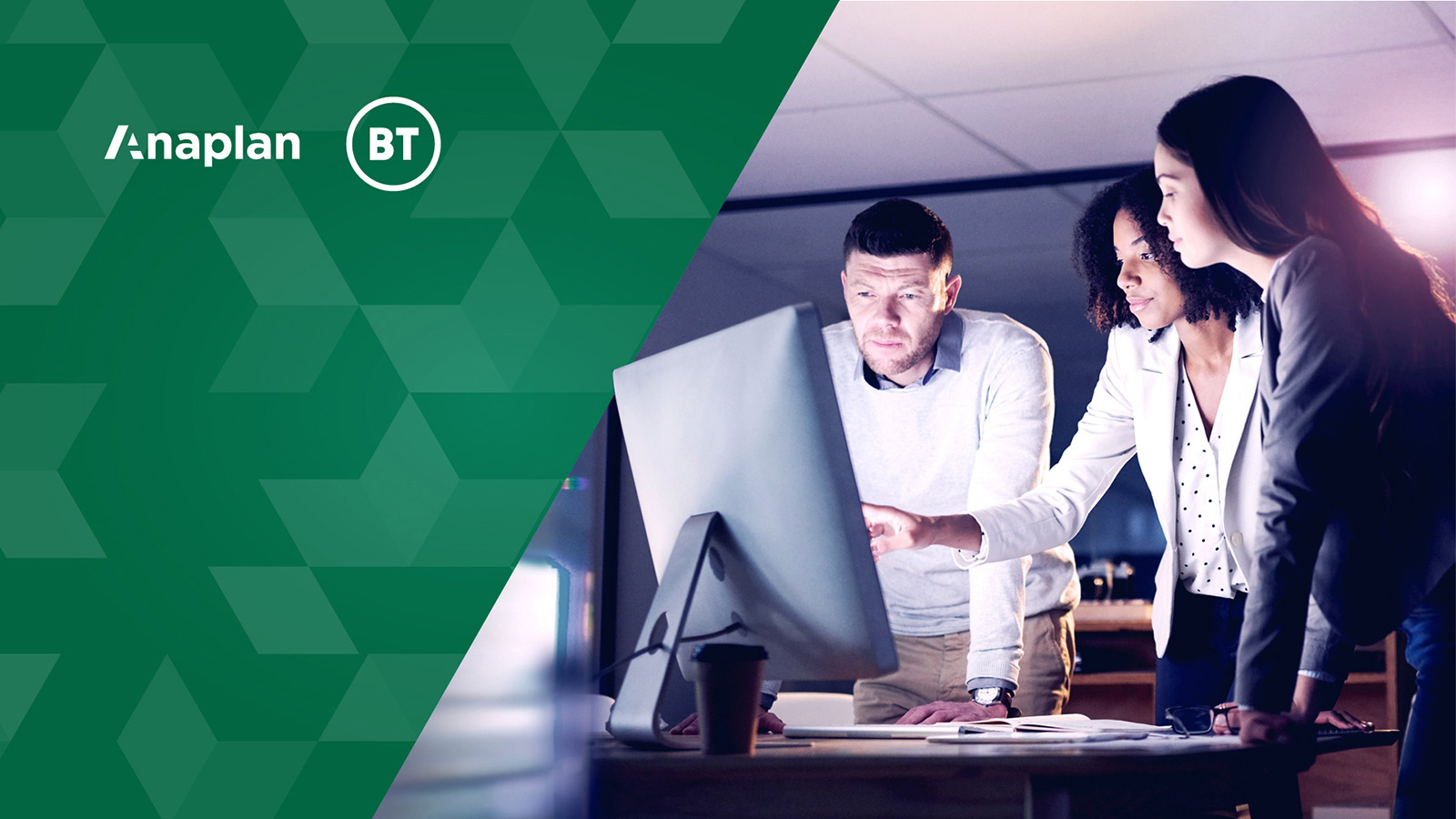 three coworkers standing over a computer