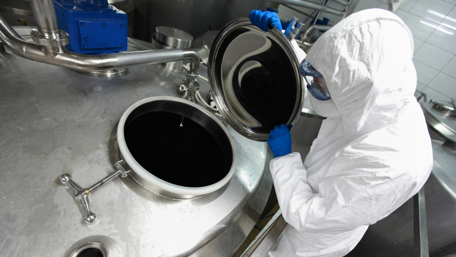 Worker in protective suit working with lab equipment