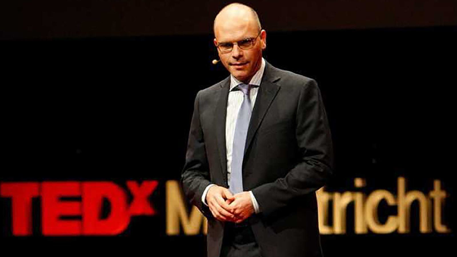 Bald man with glasses speaking at a TED Talk