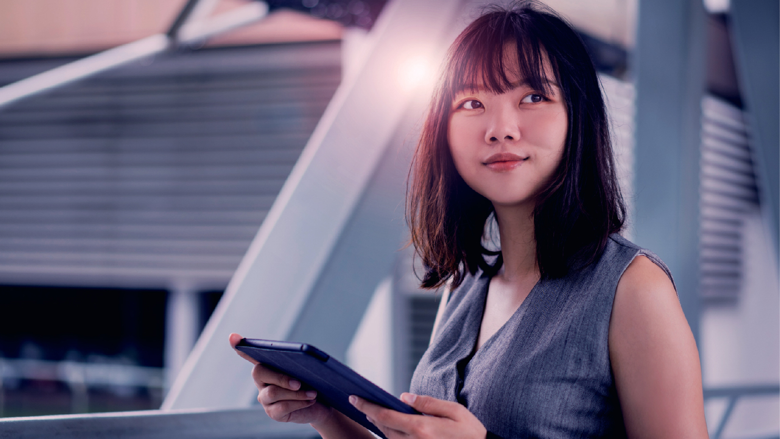 Businesswoman in professional attire holding a tablet looking contemplative