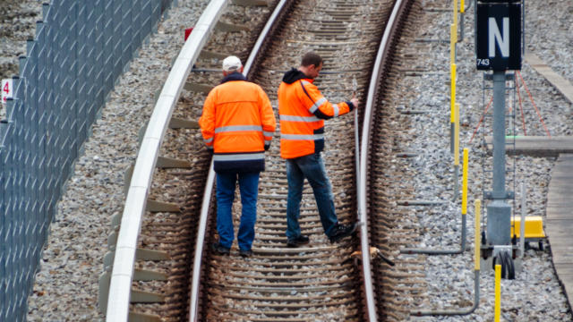 Two workers in orange high visibility jackets working on railroad