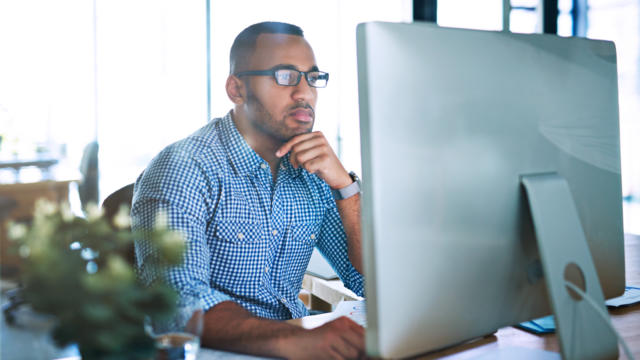 Professional businessman wearing clean semi-professional clothing while looking intently at his computer monitor